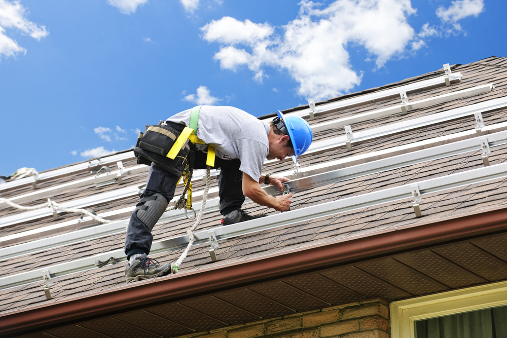 Man installing rails for solar panels on residential house roof